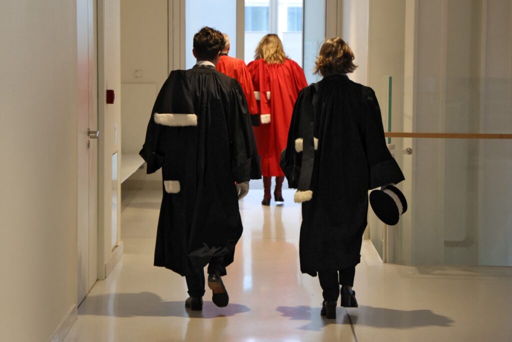 Des magistrats en robe marchent dans un couloir.